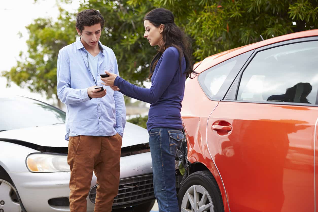 Two Drivers Exchange Insurance Details After Accident On Moblie Phones.