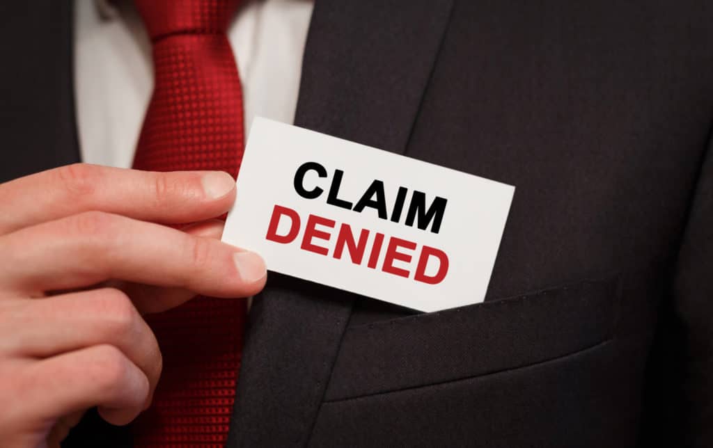 Businessman putting a card with text Claim Denied in the pocket